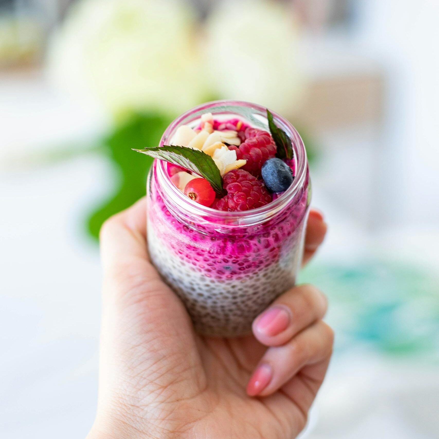 Delicious yogurt parfait with chia seeds, blueberries, and raspberries in a clear jar.